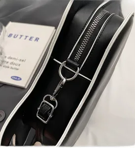 Detail of silver zipper and buckle on black leather bag with white edge stitching