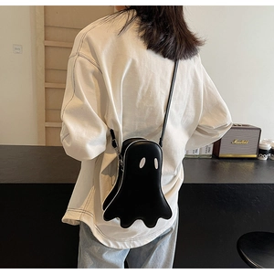 Close-up of ghost-shaped crossbody bag worn over shoulder with artistic interior background