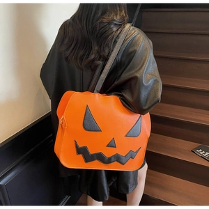 Detail of the large orange pumpkin tote bag with a black smiling face on a leather jacket