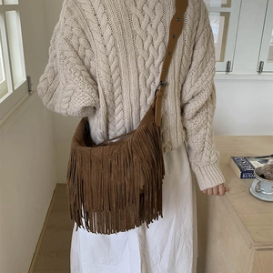 Brown suede fringe crossbody bag with adjustable wide strap shown on a model