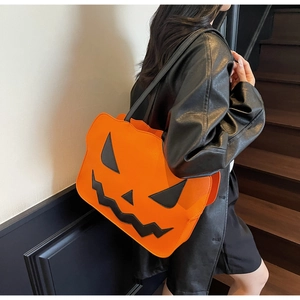 Close-up of a pumpkin-shaped orange Halloween shoulder bag with black facial details