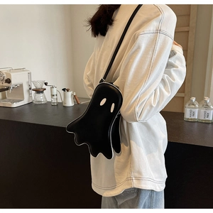 Close-up of black ghost-shaped PU leather crossbody bag with white eye detail and stitching