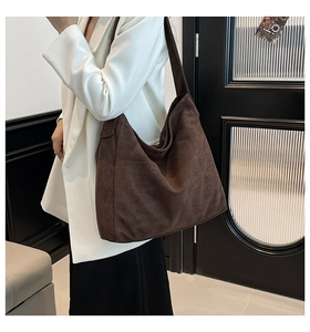 Detail view of large brown suede hobo bag worn over the shoulder showing ample capacity