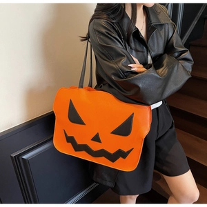 Detail of orange pumpkin tote bag with black face expression and slender straps