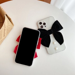 Detail of transparent phone case featuring a large black velvet bow and pearl heart