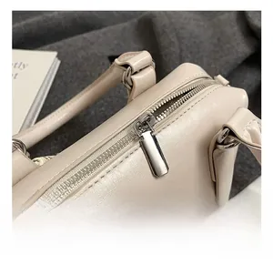 Detail view of smooth silver metal zipper and premium beige leather texture on handbag