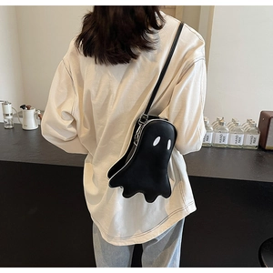 Ghost-shaped black crossbody bag in faux leather worn by a model in a cafe setting