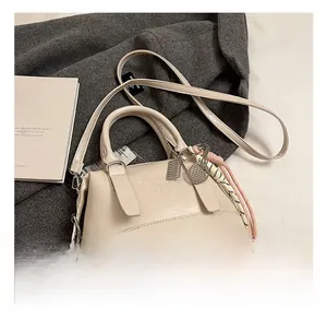 Detail of cream soft leather handbag with embossed lettering and tennis racket pendant