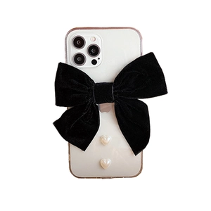 Detail of white iPhone case with large black velvet bow and two hanging pearl hearts