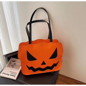 Detail of pumpkin-shaped shoulder bag with classic Jack-o'-lantern face in vibrant orange
