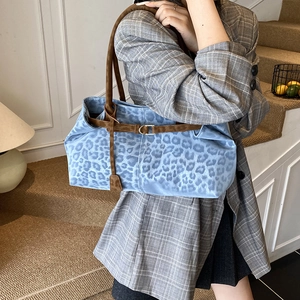 Blue leopard print tote bag with brown leather straps worn with a stylish blazer