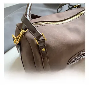 Macro detail of the golden metal hooks and shiny brown leather strap on a Boston bag