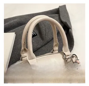 Close-up of beige faux leather handbag with soft handle and embossed letter details
