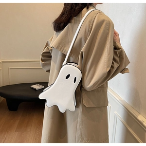 Close-up of a white ghost-shaped crossbody bag worn with a khaki trench coat