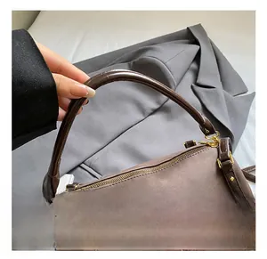 Detail of retro brown suede handbag with smooth dark brown handle and gold hardware