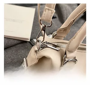 Close-up of silver metal hooks and D-rings on a cream minimalist leather handbag