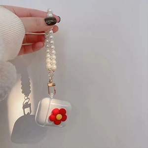 Macro shot of clear AirPods case with a red 3D flower and white pearl lanyard strap