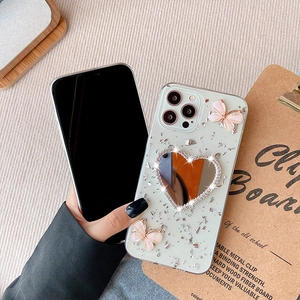 Dettaglio custodia iPhone con foglia d'argento, farfalle rosa e specchio a cuore