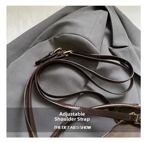 Close-up of adjustable deep brown leather shoulder strap with gold-tone hardware