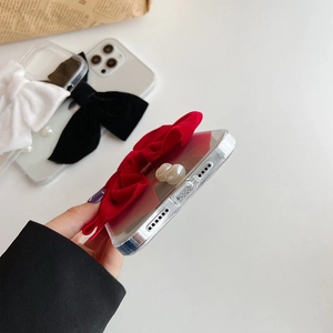 Detail shot of iPhone case featuring a large red velvet bow and elegant pearl accents