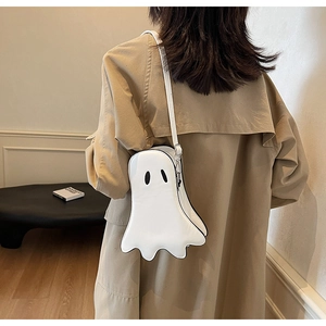 Close-up of a white ghost-shaped crossbody bag worn by a model in a cozy interior