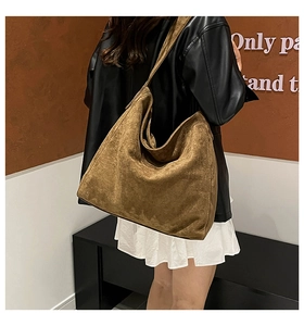 Close-up of brown suede tote bag with wide shoulder strap showing texture and large capacity