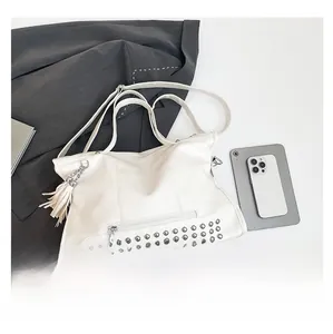 Detailansicht der weißen Leder-Shopper mit Nietenverzierung und Quasten-Anhänger