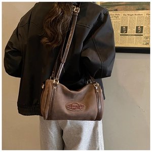 Detailed back view of a vintage brown suede Boston crossbody bag worn by a model