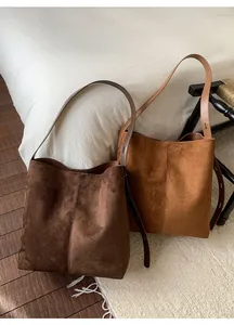 Detailansicht matter Wildleder-Beuteltaschen in Dunkelbraun und Hellbraun mit weichem Griff
