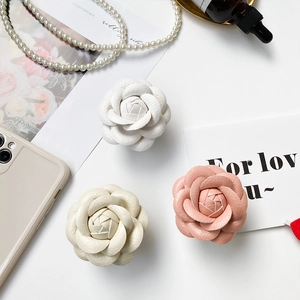 Detailed view of elegant camellia floral air bag phone stands in white and pink leather