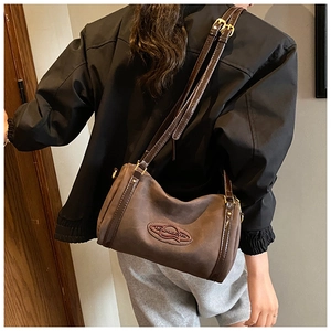 Detail of a dark brown matte Boston bag showing texture and leather trim on a model