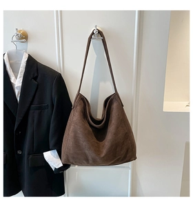 Detail of a dark brown suede hobo tote bag styled with a professional black blazer