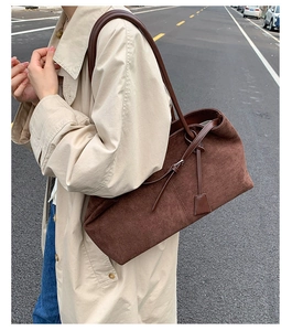 Detail of dark brown suede tote bag with leather strap on a beige trench coat