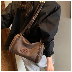 Detail of brown suede Boston bag with leather strap and golden metallic hardware
