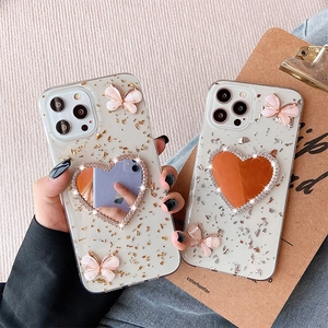 Dettaglio custodia iPhone con specchio a cuore, farfalla 3D e finitura in foglia d'oro