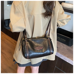 Detail of black cylindrical Boston bag with brown contrast straps and leather texture