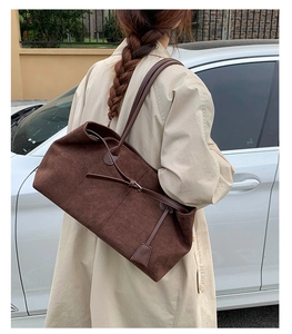 Detail of dark brown faux suede tote bag with slim leather straps and retro buckle accents