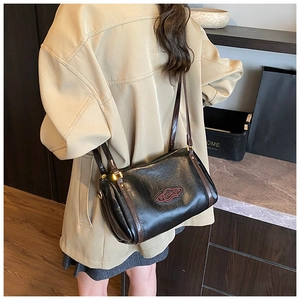 Detail view of a vintage black cylindrical Boston bag with adjustable brown shoulder strap