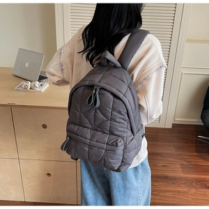 Detail of dark grey quilted backpack showing plush padded texture and sturdy shoulder straps