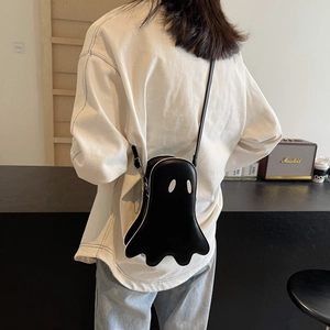 Chic black ghost shaped crossbody bag with white eyes on a female model outdoors