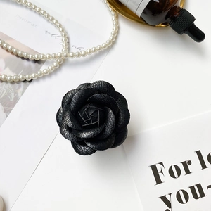 Detailed view of a 3D black leather camellia phone grip with elegant pearl background