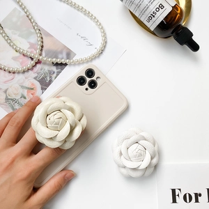 Detail view of cream camellia flower grip with lychee leather texture on a beige phone case