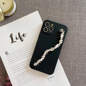 Macro shot of a luxury black iPhone case featuring a sparkling marquise rhinestone hand chain