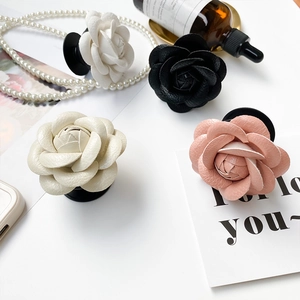 Detailed view of four 3D camellia flower phone grips in black, white, and pink leather