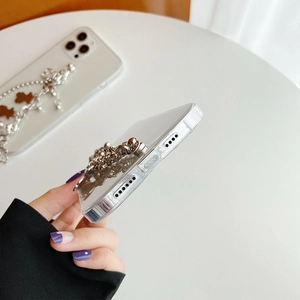 Detail view of transparent phone case featuring a silver metal chain with a bear charm