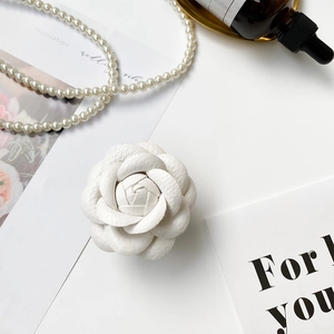 Detail showing white camellia phone stand with premium lychee grain leather texture