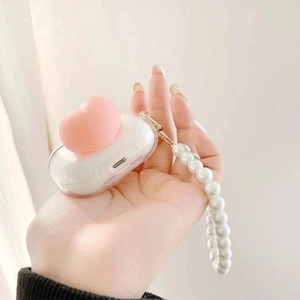 Detailed view of clear AirPods case with pink 3D heart and pearl lanyard strap