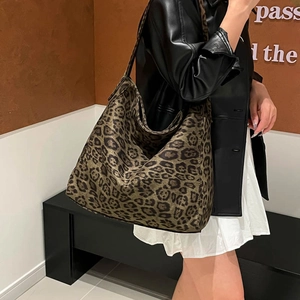 Large leopard print faux suede hobo tote bag worn by a model in a trendy casual style