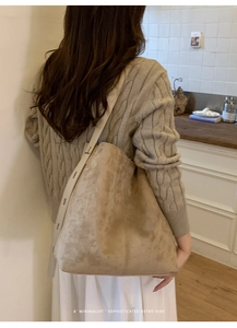 Minimalistische beige Wildleder Beuteltasche mit breitem Gurt an einem Model