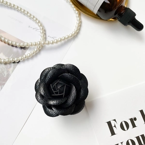 Detail of 3D camellia phone grip in black faux leather texture with elegant accessories